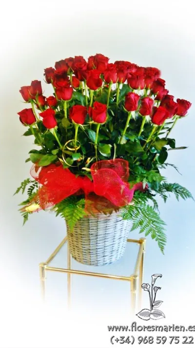 Cesta de mimbre con rosas rojas, helecho y lazo de malla rojo