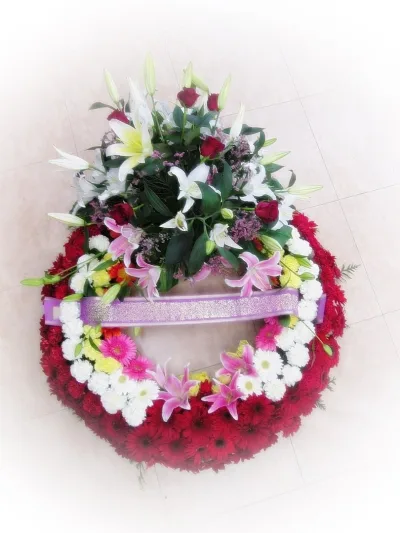 Funeral wreath of red gerberas and white chrysanthemums with a spray of lilies and red roses