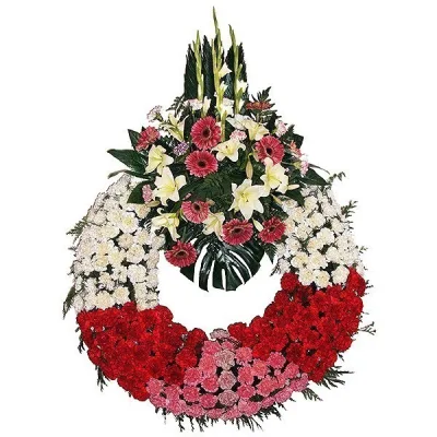 Funeral wreath of white, red and pink carnations with a spray of gerberas and white lilies