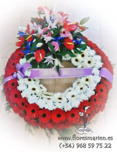 Funeral wreath of red and white gerberas with a spray of anthurium, lilies and iris and a lilac ribbon