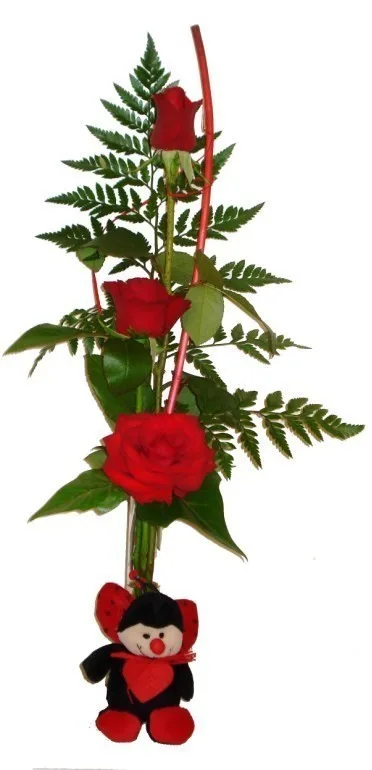 Composición vertical de tres rosas rojas con helecho y un peluche de mariquita