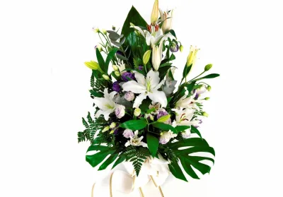 Ramo de condolencias con lilium blanco, lisianthus lila, eucalipto y hojas de monstera
